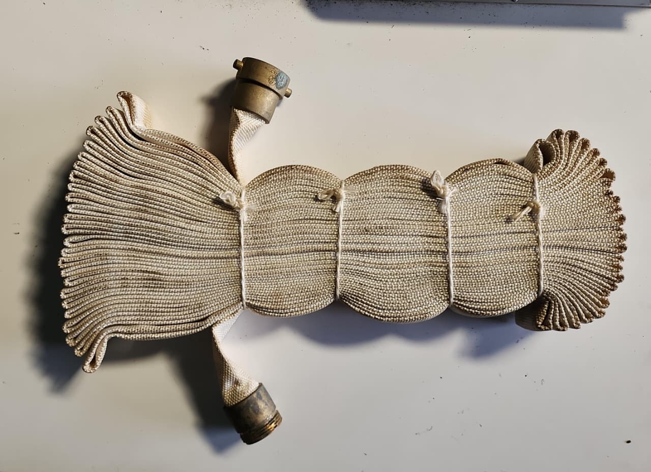 Manguera de bomberos enrollada con acoplamientos metálicos